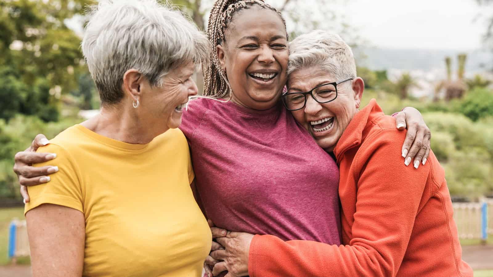 3 senior women hugging and smiling.