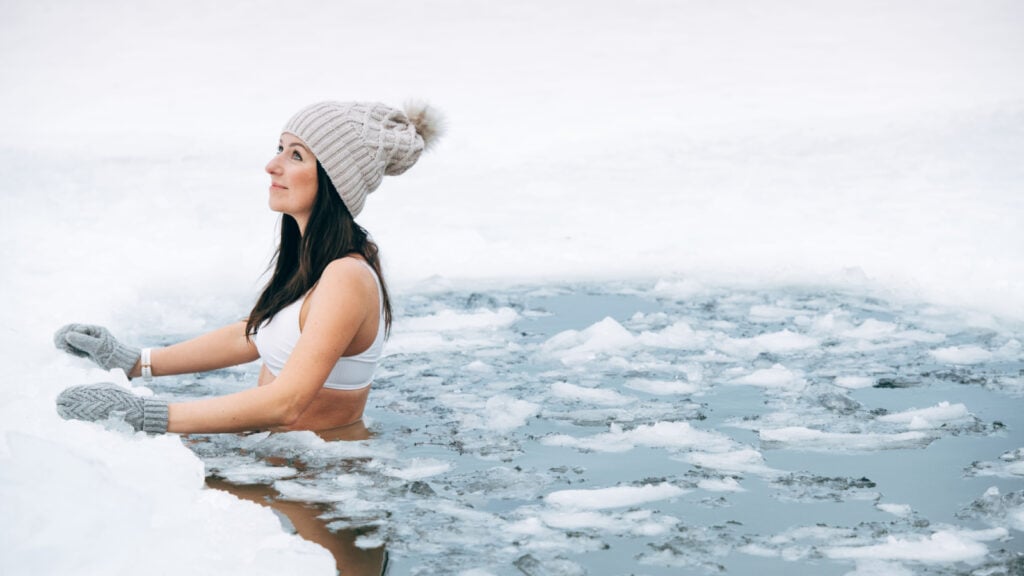 Sweden. Woman in hat and gloves in ice water.