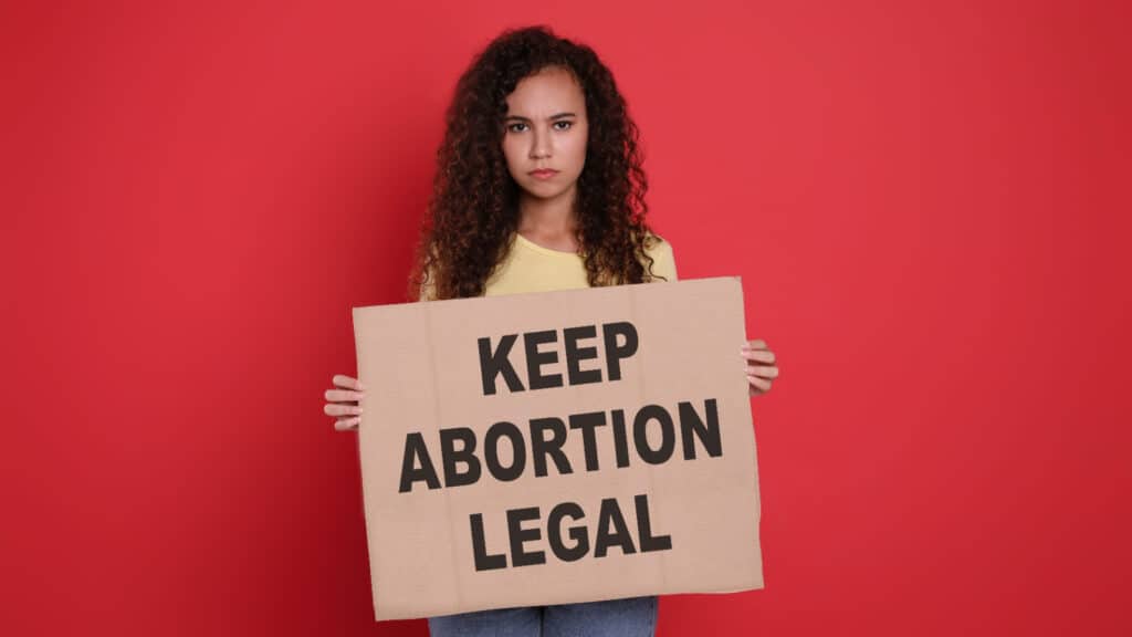 Woman holding Keep Abortion Legal sign.