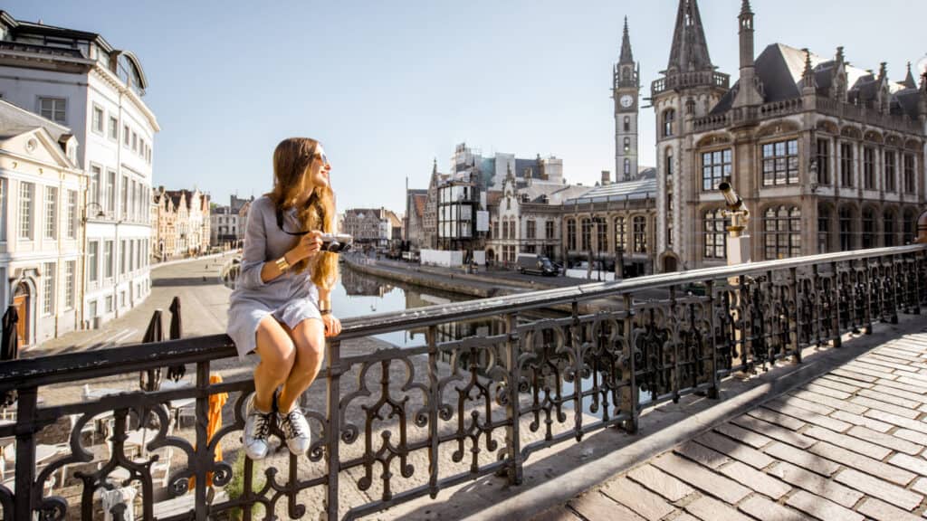 Woman sitting on fence in Belgium. 