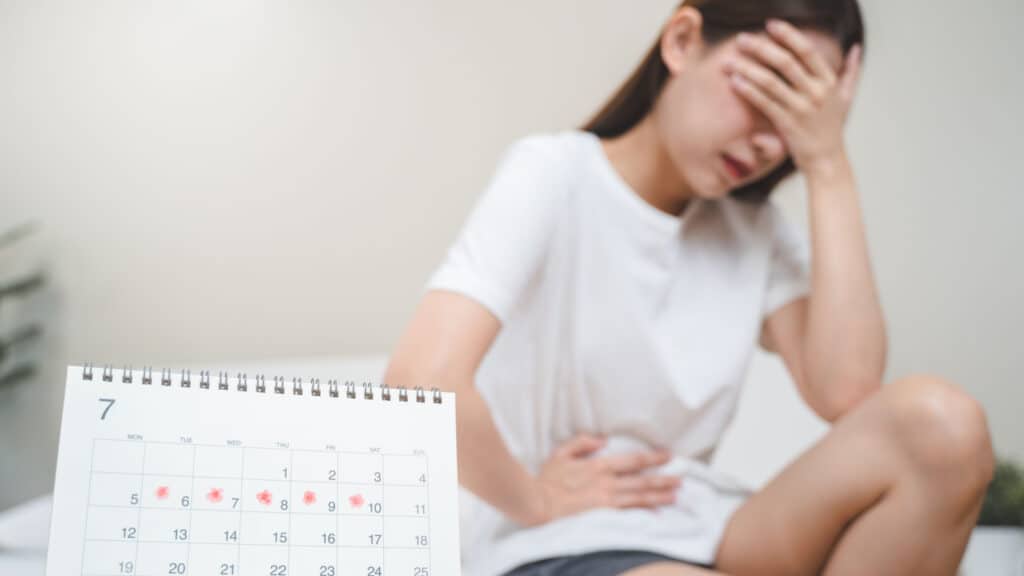 Young girl with menstrual pain and calendar.