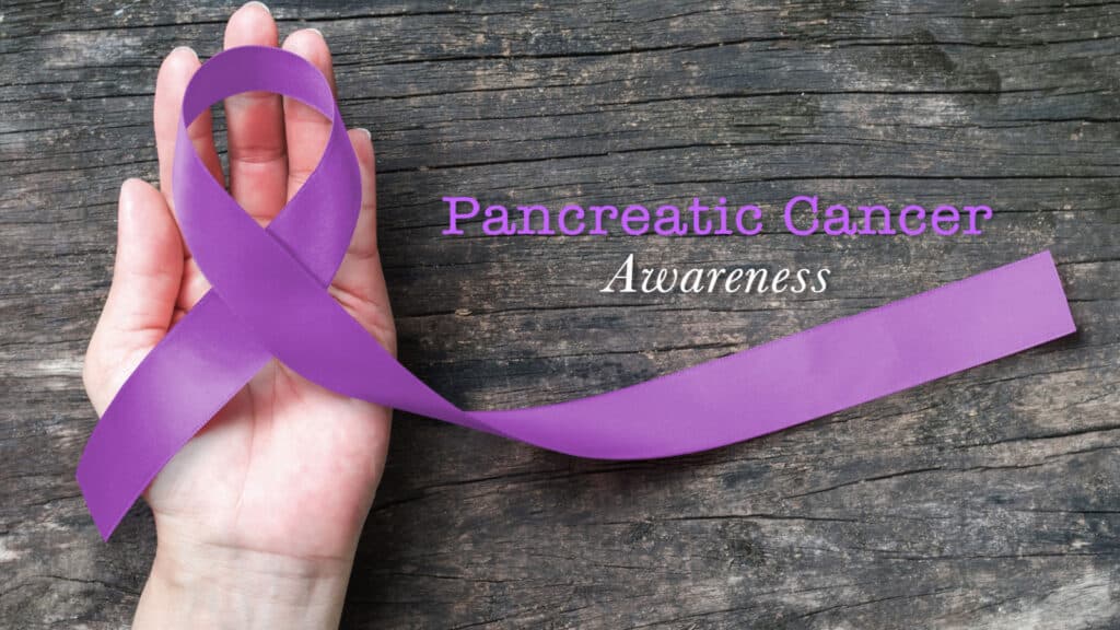 hand holding purple ribbon for pancreatic cancer awareness. 