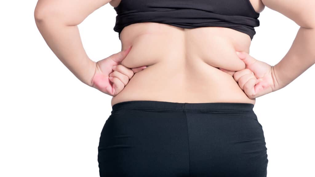 woman pinching back fat. 