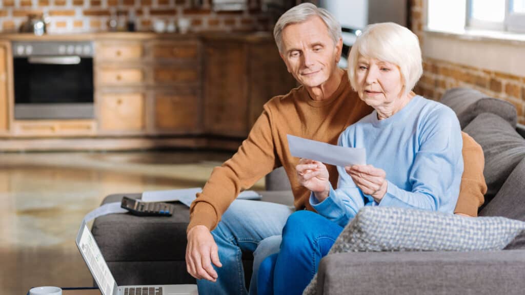 Older couple on couch looking at check. 