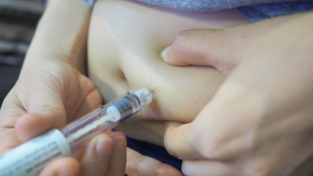 Woman giving self injection in stomach. 