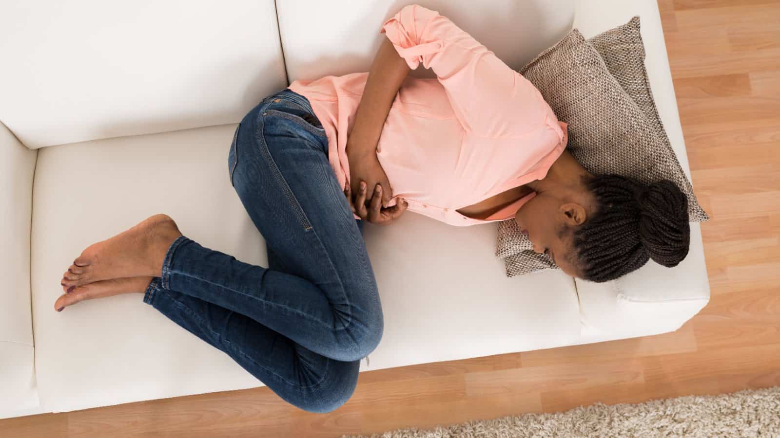 woman lying on couch with stomach pain.