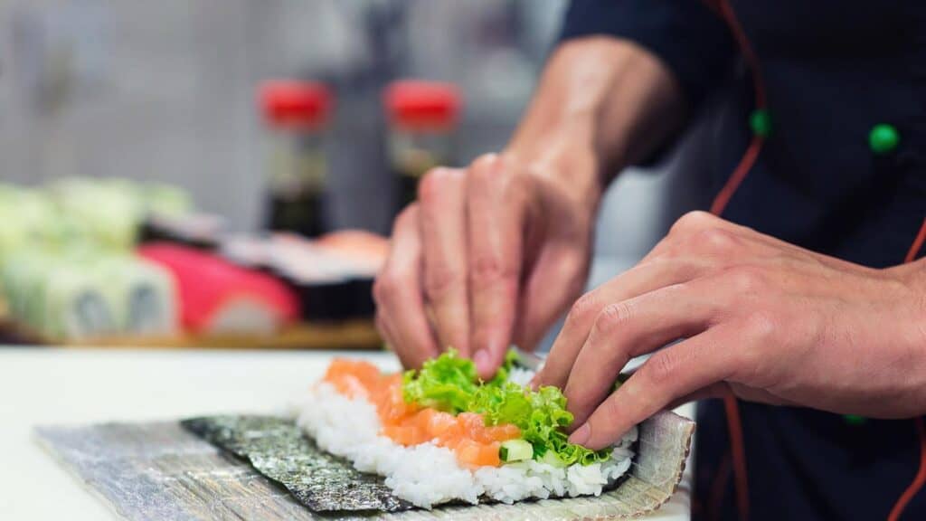 close-up-of-hands-rolling-sushi-using-bamboo-mat.