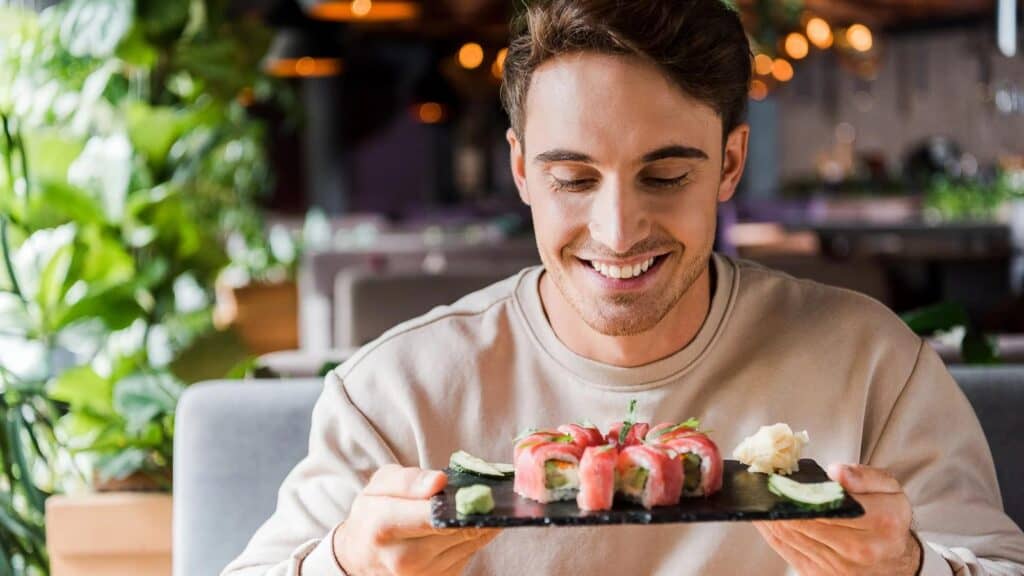 man-holding-sushi-on-dark-platter.