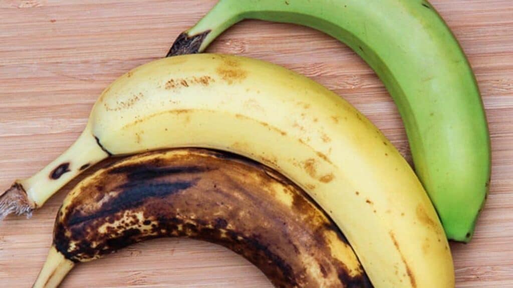 varying-degrees-of-ripeness-of-bananas-3-bananas-on-a-wooden-board.