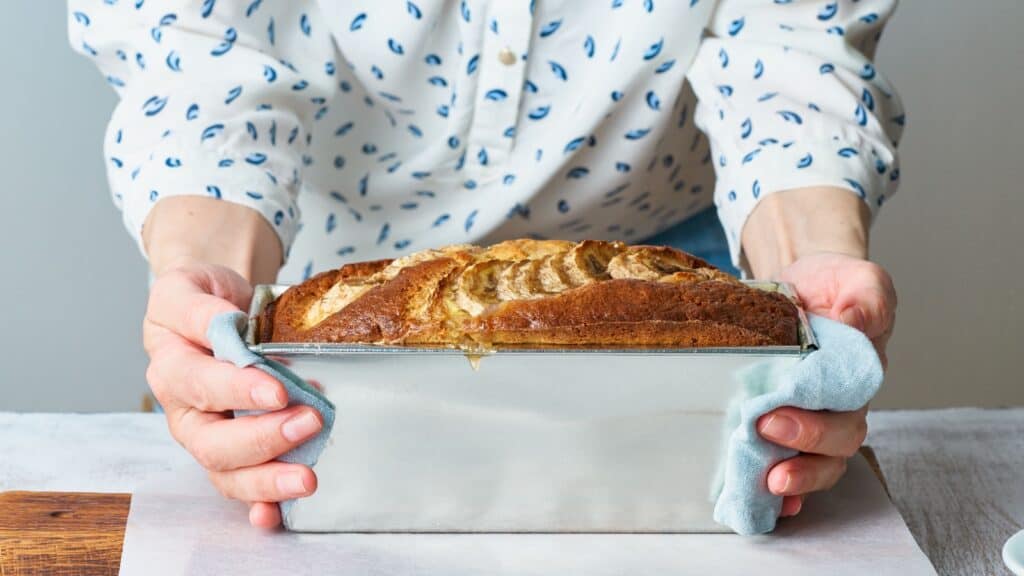 woman holding loaf pan of banana bread. 