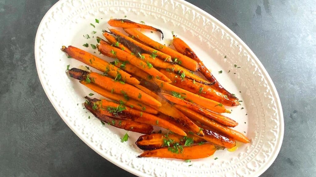 Honey-Lemon-Roast-Carrots-on-white-oval-platter-on-dark-background