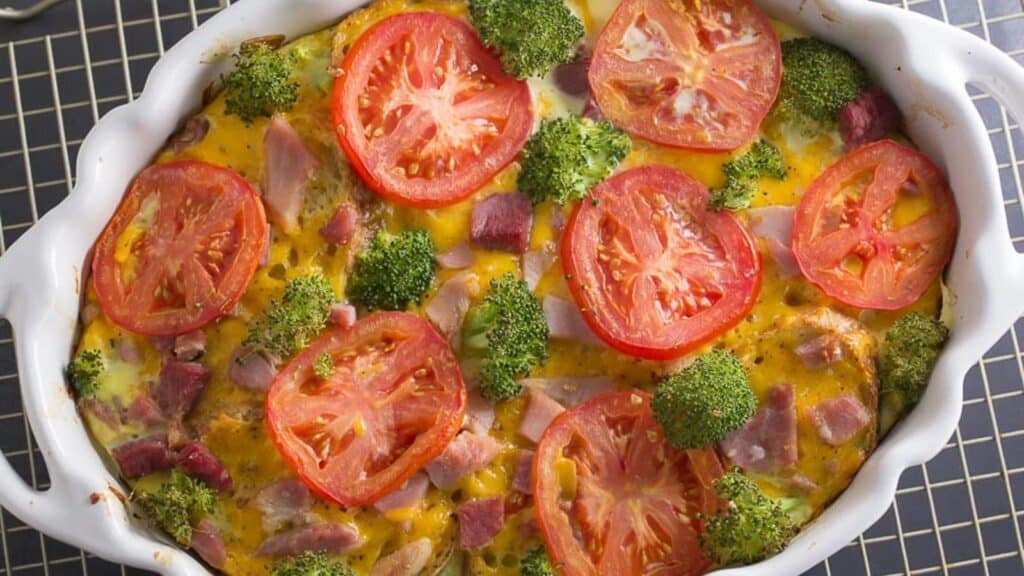 overhead-of-savory-bread-pudding-in-white-oval-casserole-with-broccoli-and-tomato.