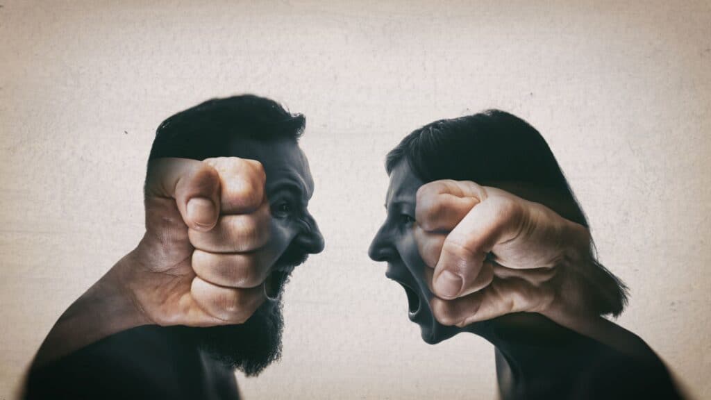 Double exposure image. A man and a woman scream at each other, their silhouettes are combined with a picture of fists to enhance drama.