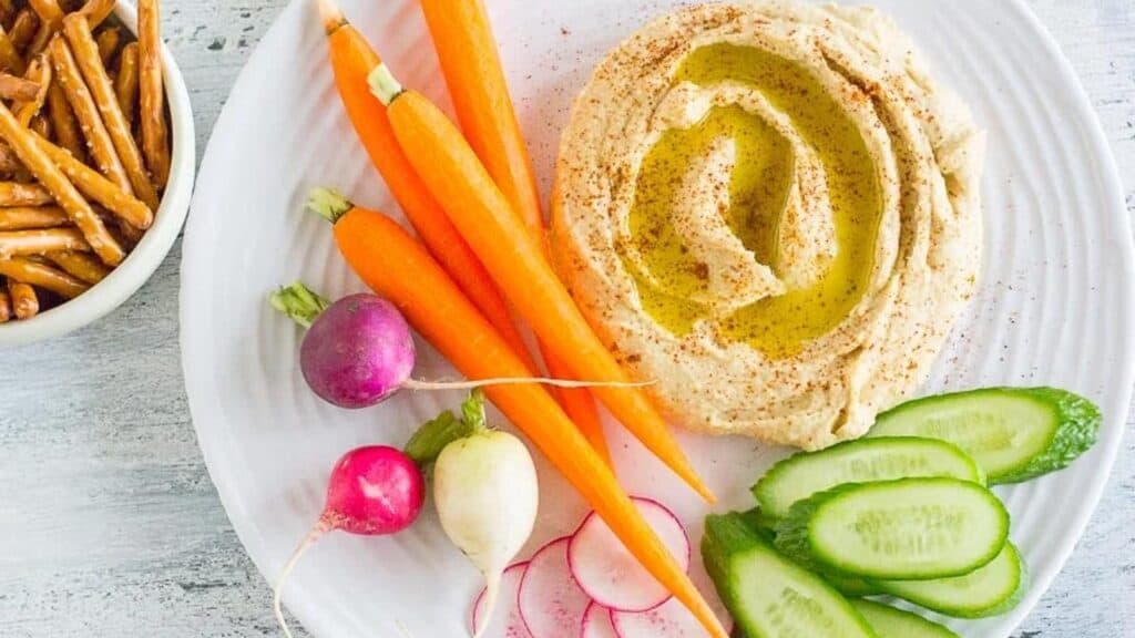 hummus-on-a-white-plate-with-low-FODMAP-vegetables-and-gluten-free-pretzels.