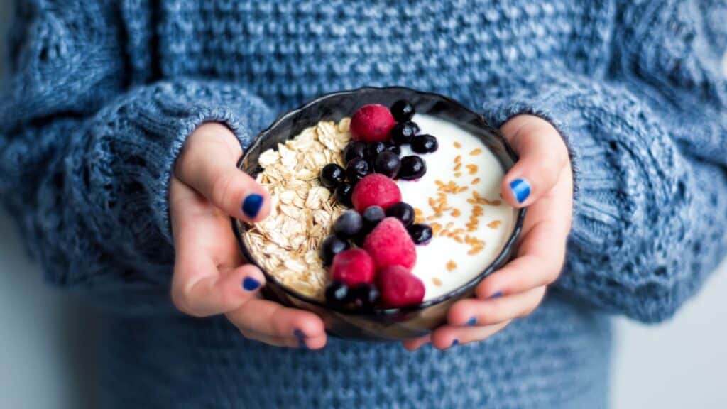 woman holding bowl of oats and berries.