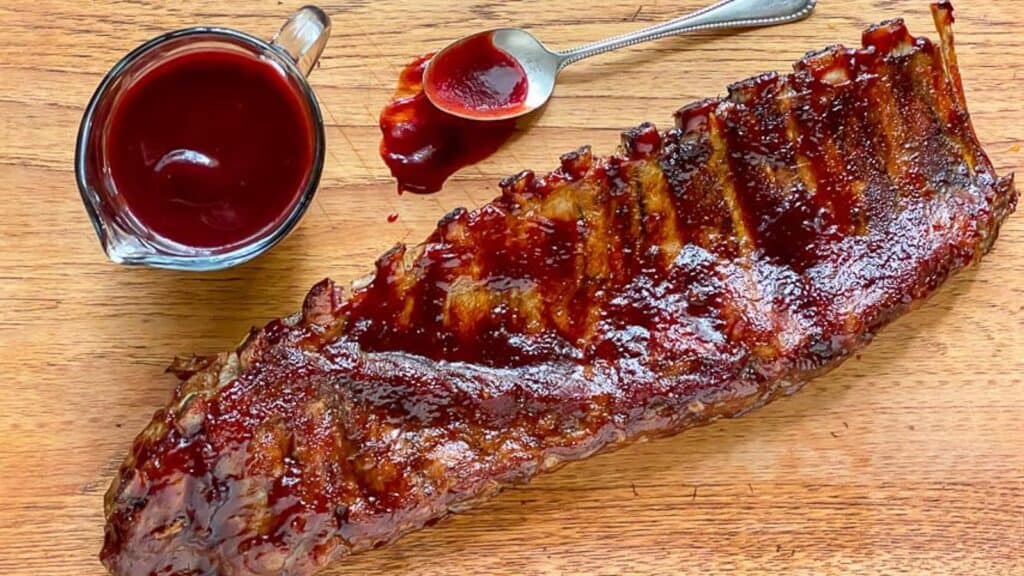 Blackberry-Maple-Rib-rack-on-wooden-board-with-extra-sauce.