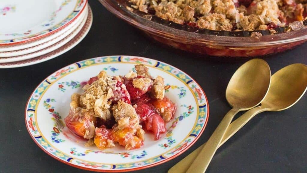 horizontal-image-of-strawberry-peach-crisp-on-a-decorative-plate-and-in-pie-plate-in-background.