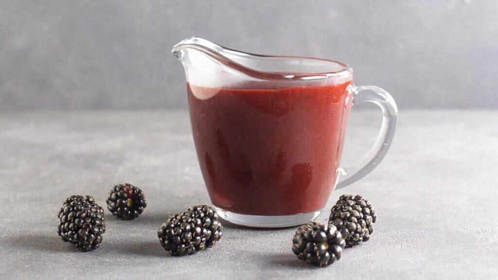 side-view-of-Blackberry-Maple-BBQ-Sauce-in-clear-pitcher-dark-table.