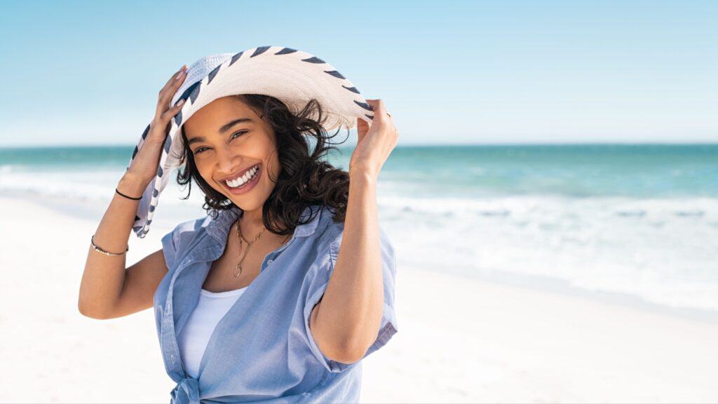 Happy woman on beach in hat.
