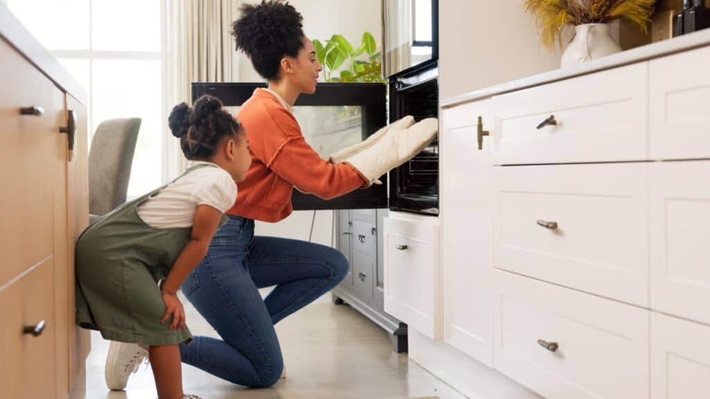 Mother daughter looking in oven. 