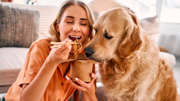 Woman sharing food with dog.