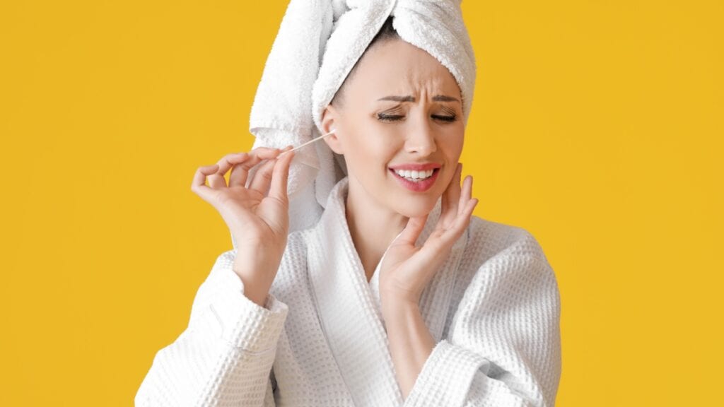 Woman using Q Tip in ear.