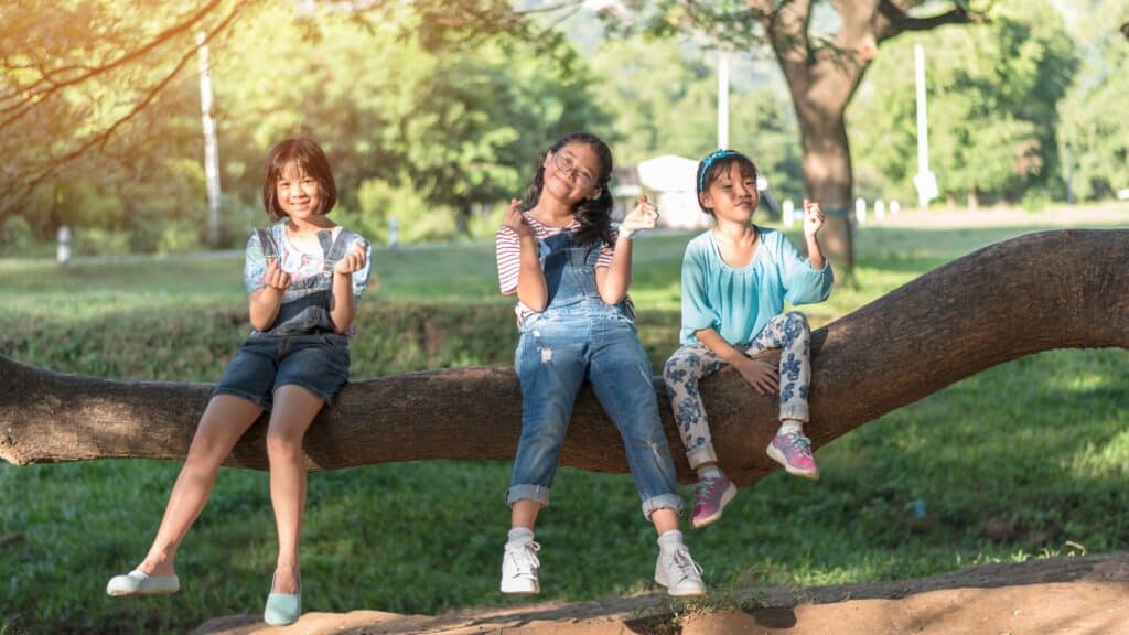 kids on tree branch in shade.