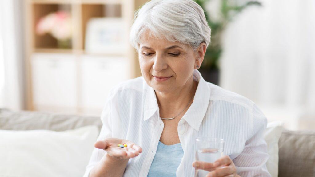 Senior woman taking pills. Vitamins.