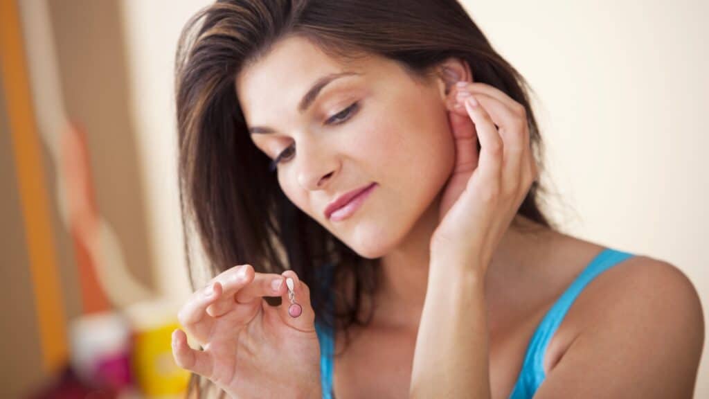 woman putting earrings on.