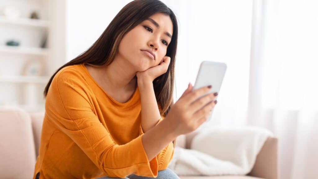 woman using phone. Looking critical.