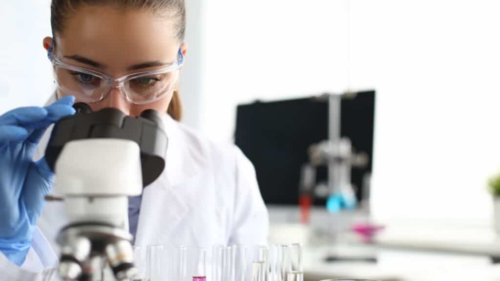 Female scientist looking in microscope.