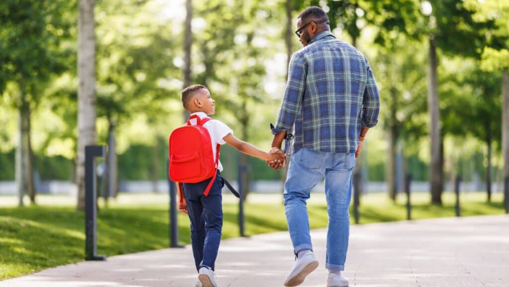 kid and dad holding hands.