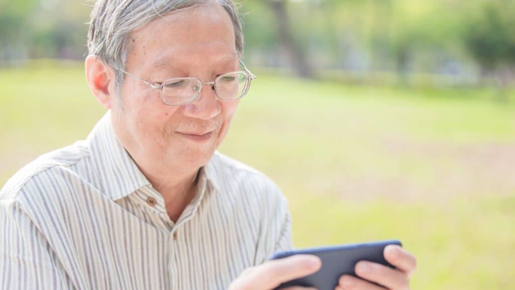 older Asian man. looking at phone. 